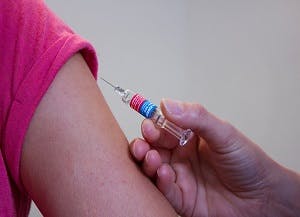 This image shows a needle being injected into someone's arm. It is an example if a vaccination.